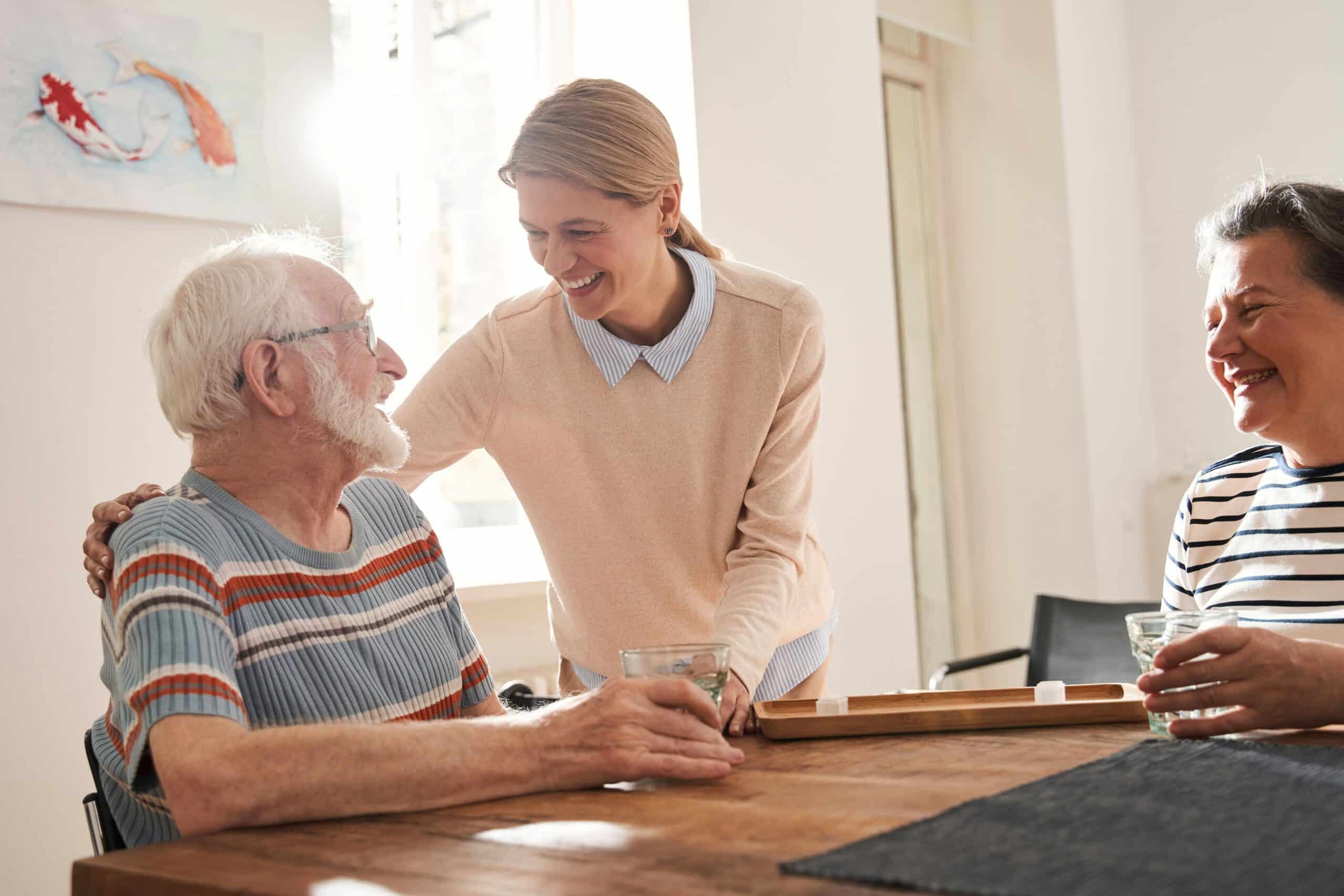 “Daughter and elderly father sharing tea and laughter in a cozy dining room in Colorado”